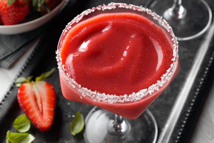 Strawberry Margarita served on black tray with strawberries and mint leaves