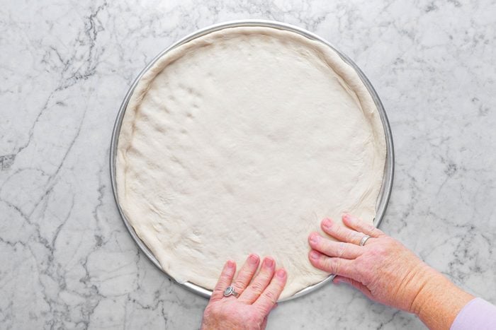 making the pizza dough into a pizza shape