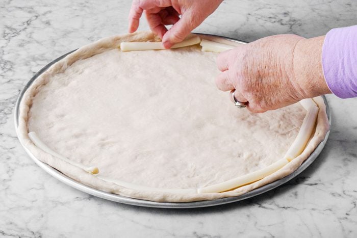 putting cheese sticks on the pizza dough