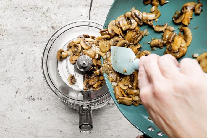 pouring cooked mushrooms into a food processor