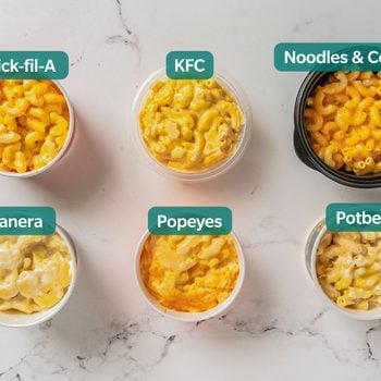 6 cups of mac and cheese from different fast food brands on a marble surface