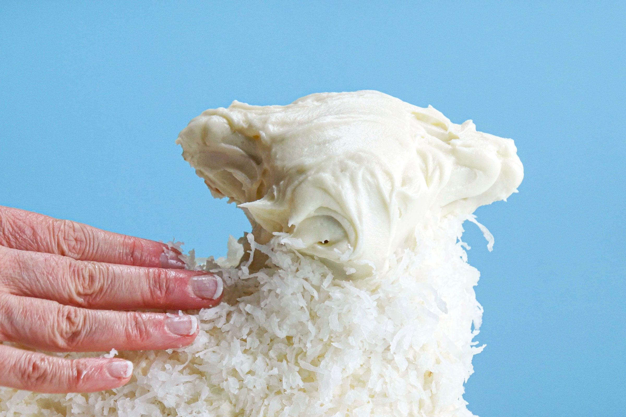 putting frosting and coconut on Easter Lamb Cake close up