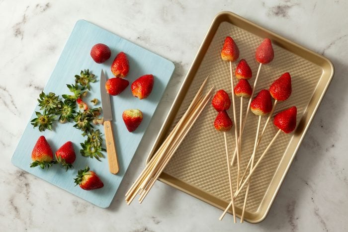 Fresh strawberries on a countertop with a wooden skewer
