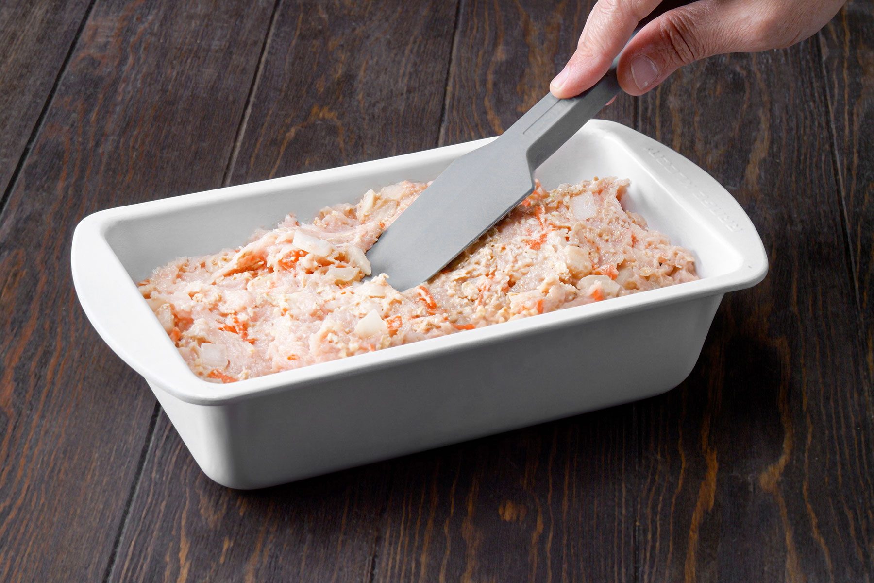 Spreading meat mixture in baking pan with spatula