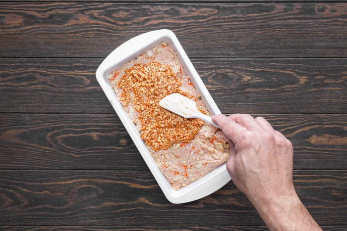 Spreading the topping on the meat mixture ion baking tray