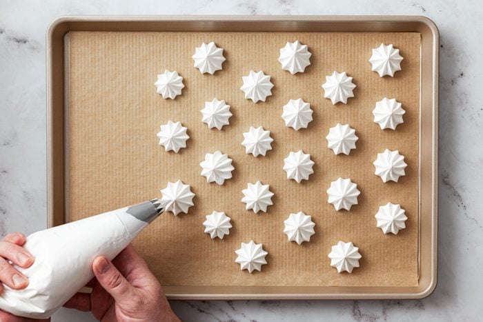 Vanilla Meringue cookies placed onto parchment-lined baking sheet.
