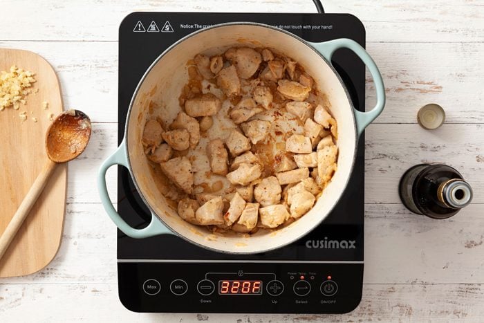 Cooking chicken pieces and diced onions on a wooden surface