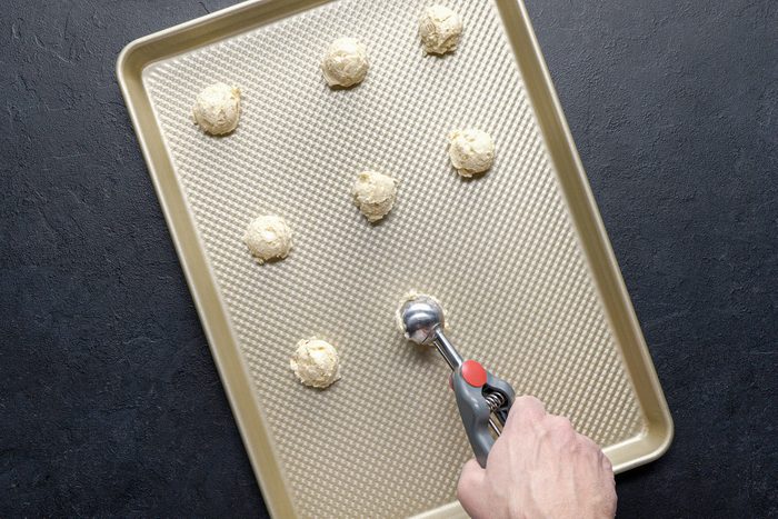 Scooping out cookie dough mix on baking tray