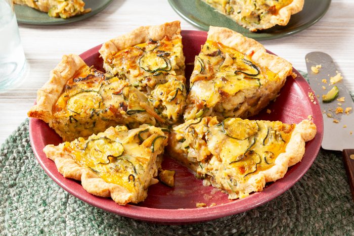 Zucchini Quiche in a Red Pie Plate on a Green Round Jute Rug