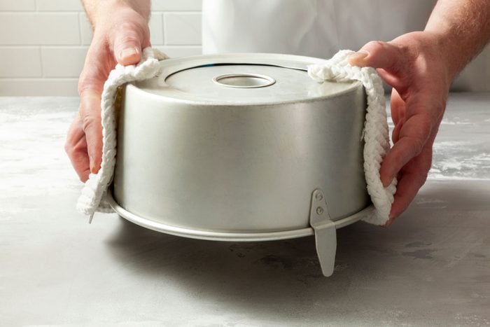 A person holding a pan invertedly with a piece of cloth