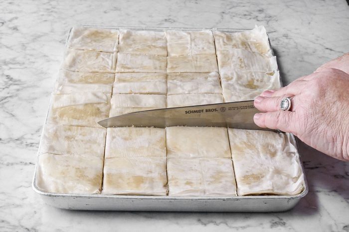 Cutting the uncooked Baklava into rectangles with knife