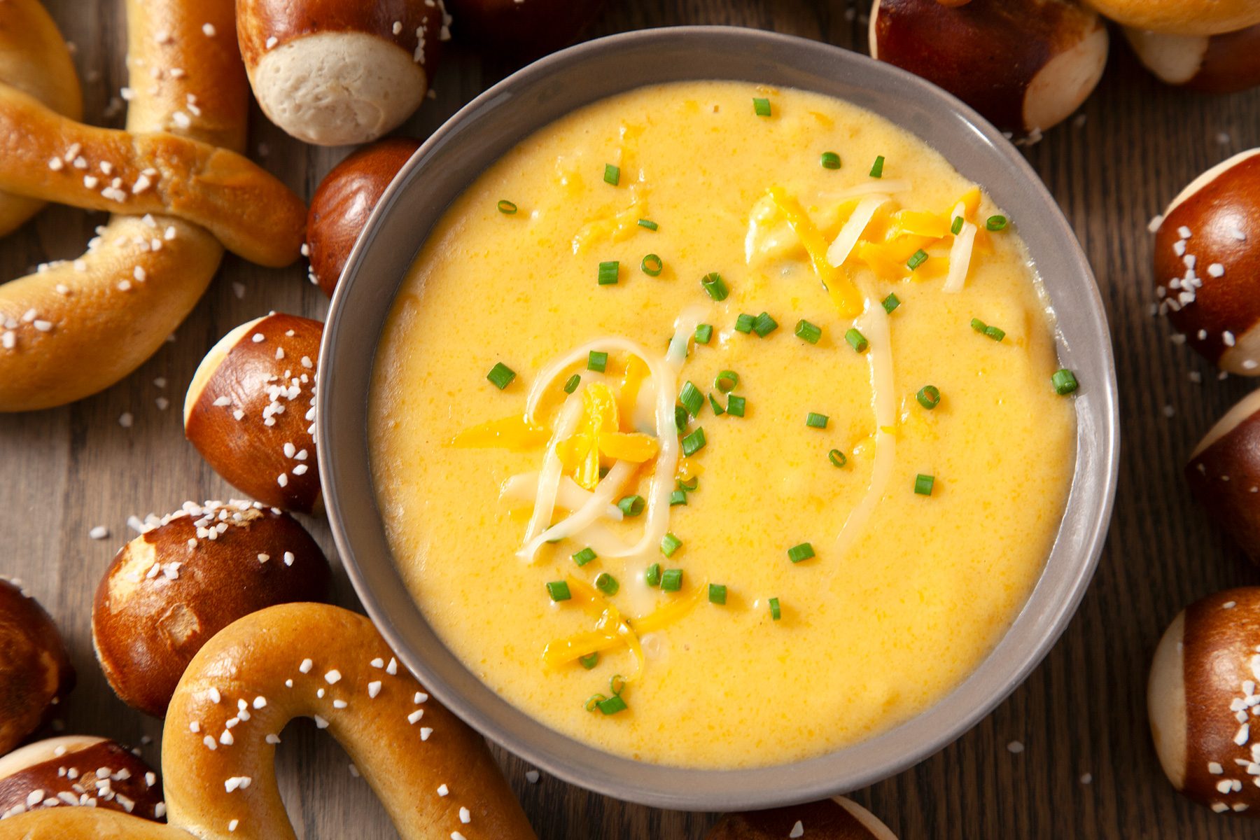 A bowl of beer cheese dip next to pretzels