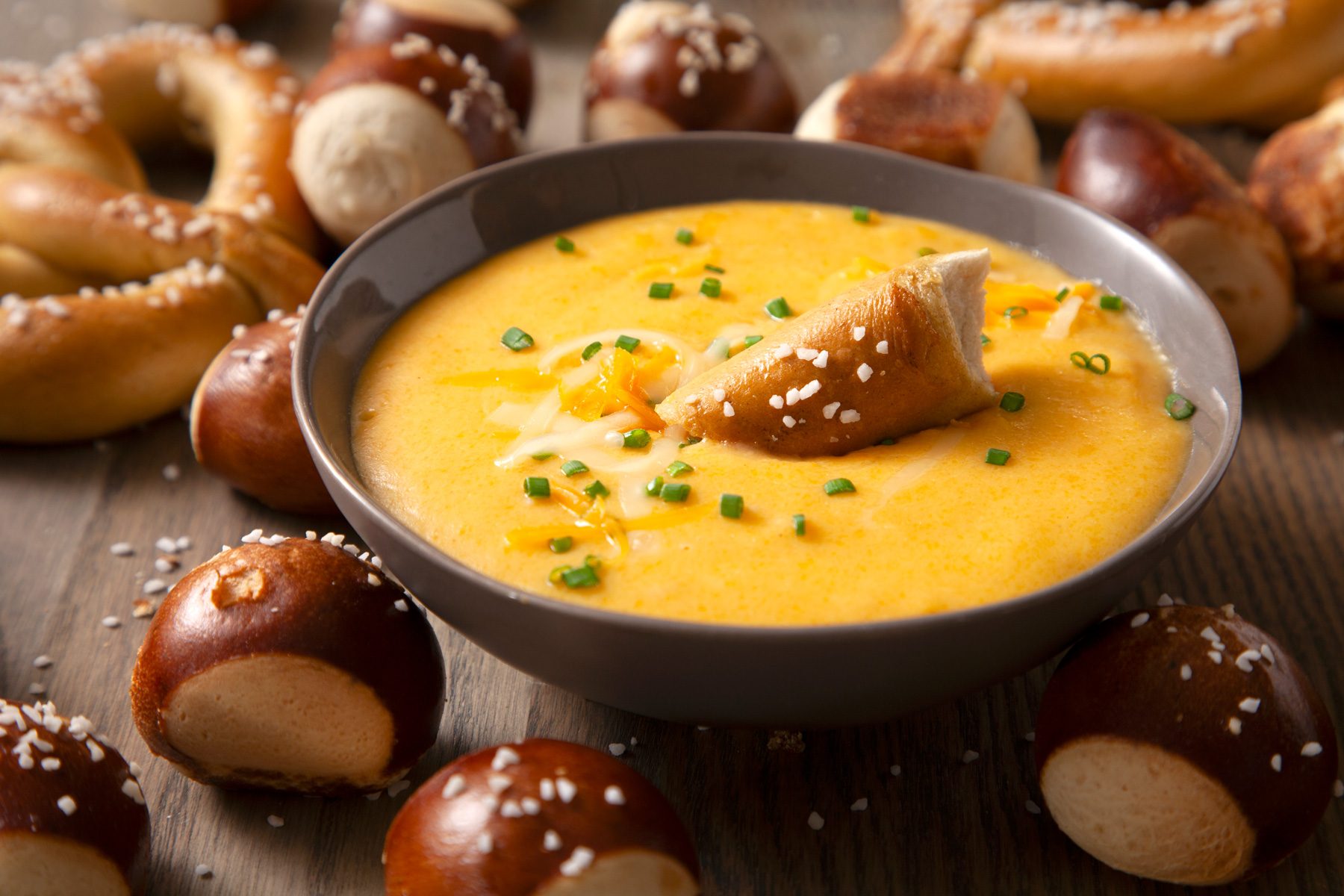 A bowl of beer cheese dip with pretzels on the side