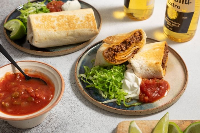 Burritos with sour cream and salsa served on small round plates