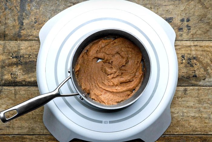refried beans in a saucepan on an induction cooktop on wooden surface