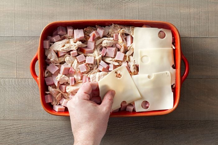Layering the chicken, ham, and cheese in a baking dish