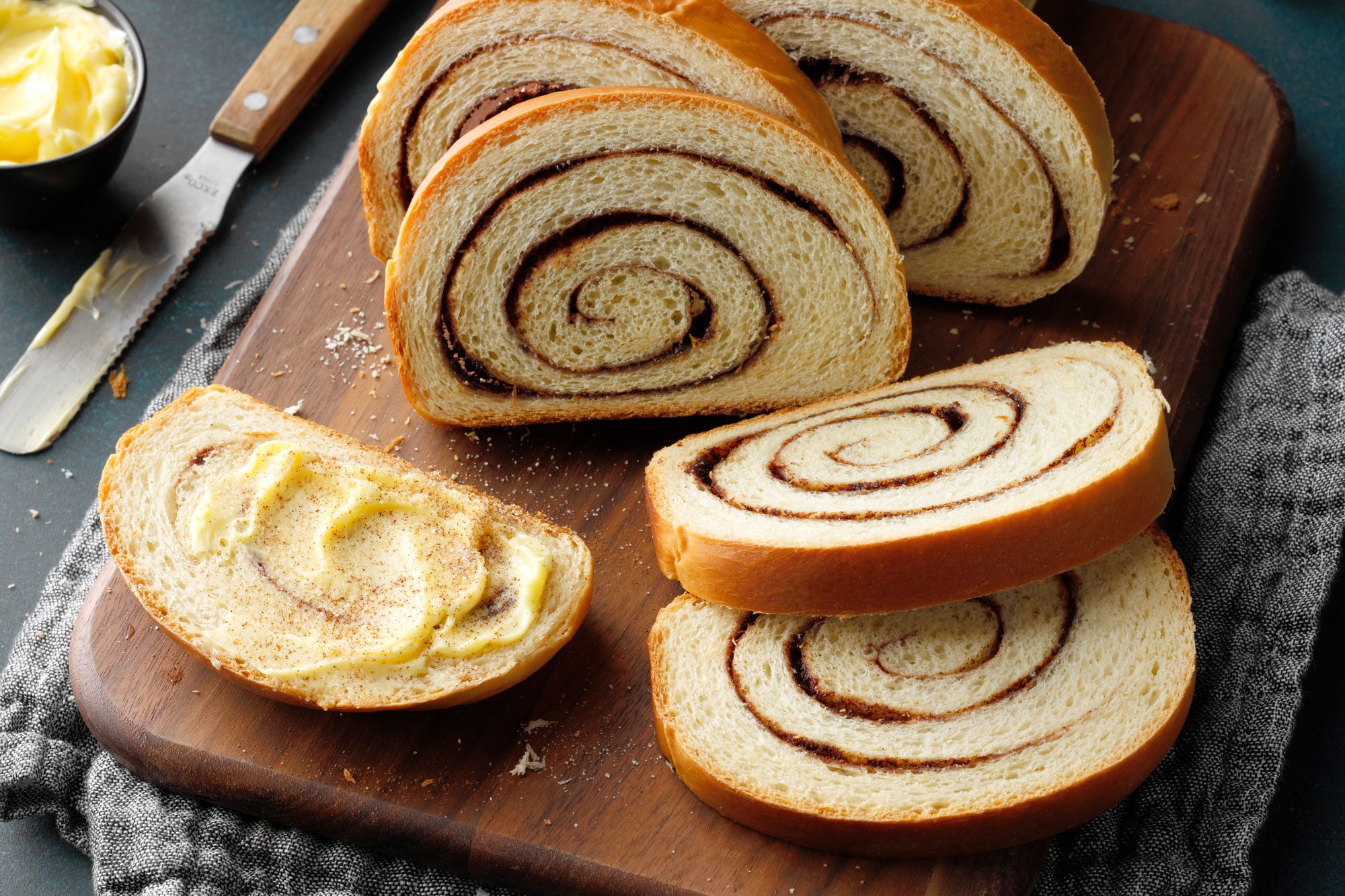 Delicious Cinnamon Swirl Bread served with butter on a wooden board
