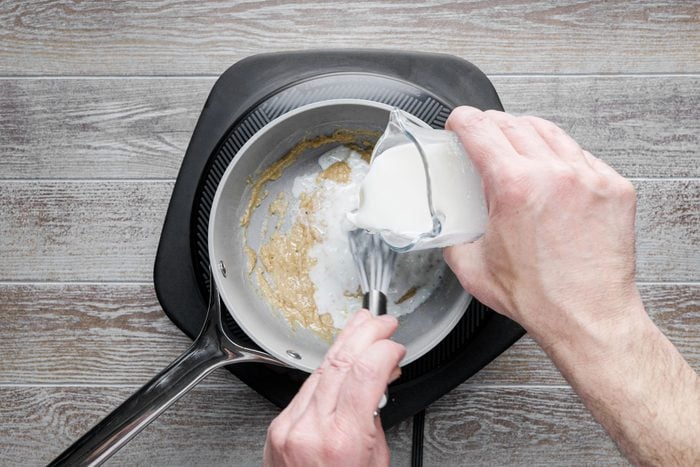 Pouring the milk in to the mixture in a small saucepan