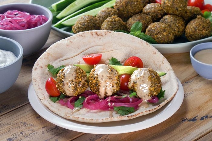 Falafel served on pita bread with sauce and vegetables on top