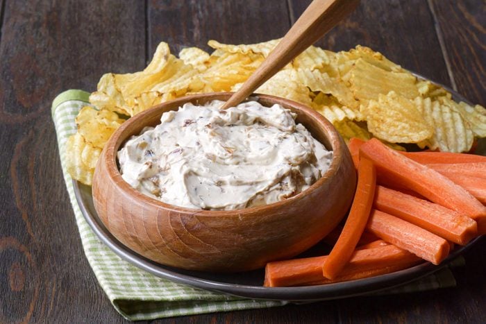 French Onion Dip served in a wooden bowl with chips and carrots