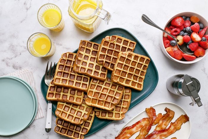A plate of waffles topped with bacon and fruit slices, a delicious breakfast spread