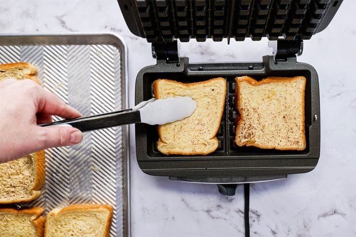 Person using waffle iron to make toast