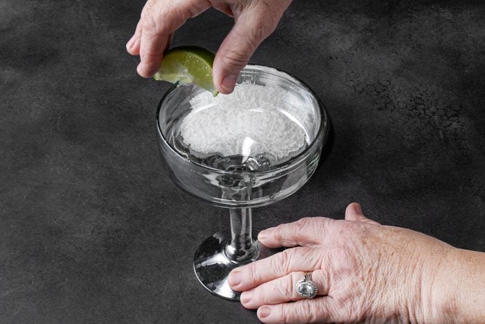 Moistening the rim of the glass with lime wedge