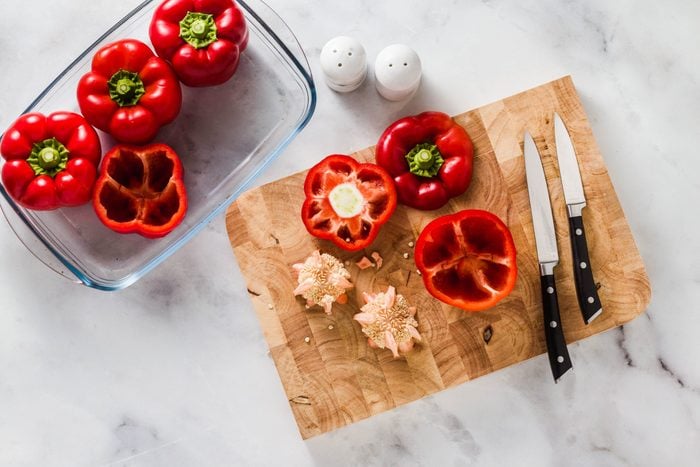 Cleaning Bell Peppers. Preparation For Filling. On A Cutting Board And A Knife. On A White Marble Table. In Glass Baking Dish