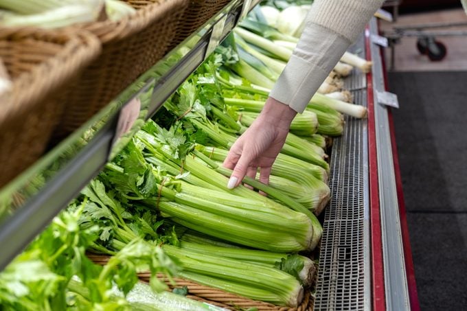 Woman picks fresh green celery at the vegetable store