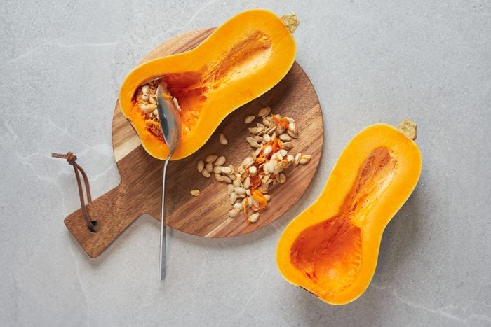 scooping out the seeds and preparing a butternut squash before freezing it
