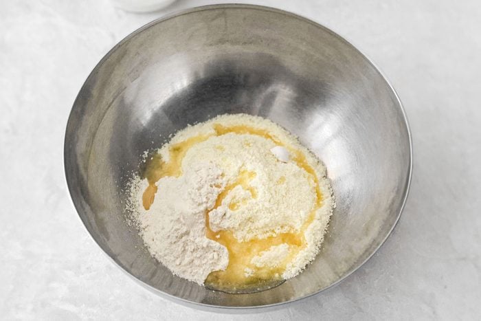 milk powder, all-purpose flour, baking powder and ghee in a large steel bowl on grey surface