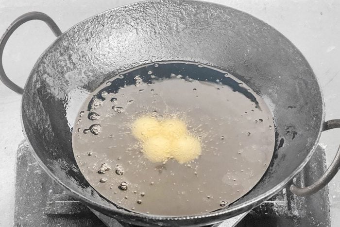 frying gulab jamun in an iron wok of hot boiling oil
