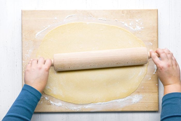 A person rolling out dough on a cutting board
