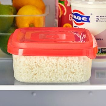 container of leftover white rice on a refrigerator shelf