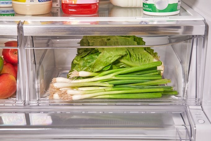 green onions in the crisper drawer of a refrigerator