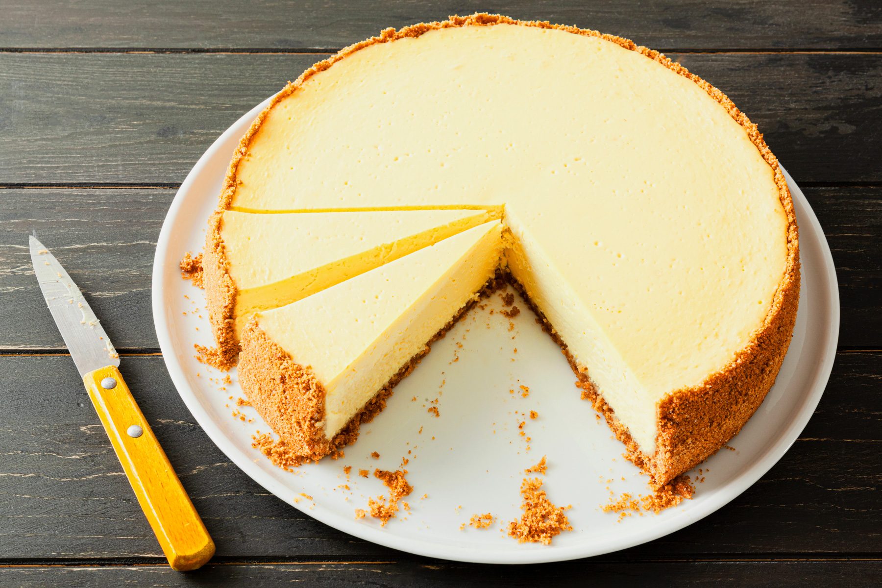 A plate of Lemon Dream Cheesecake with a knife on a wooden table