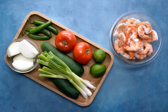 Vegetables in a tray with shrimps on bowl on a blue surface