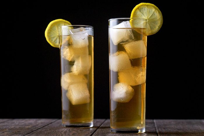 Two Highball Glasses of Long Island Iced Tea Placed on Wooden Surface with Black Background