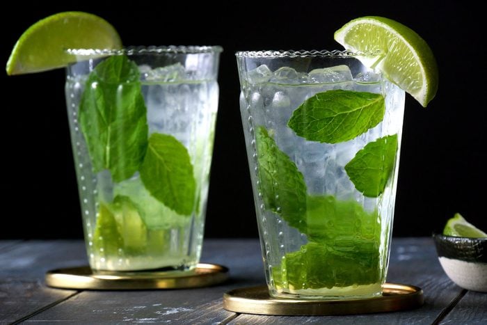 two glasses of Mojito on wooden surface with black background