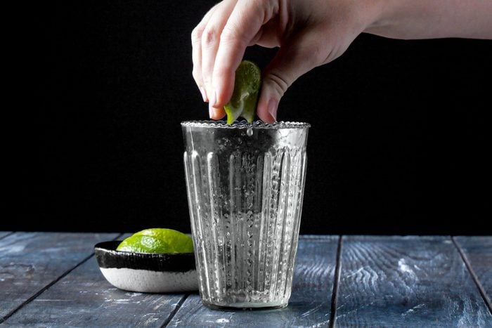 a hand squeezing lemon into a highball glass