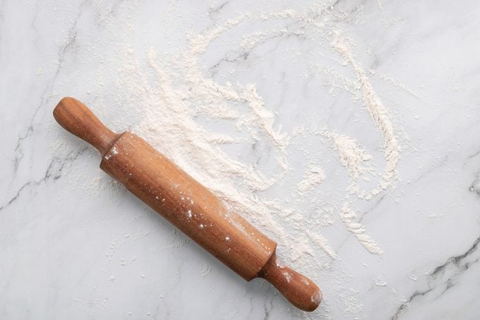 Scattered Wheat Flour And Rolling Pin Set Up On White Marble Background