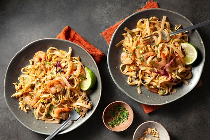 Two bowls of Shrimp Pad Thai served with slice of lemon and cilantro