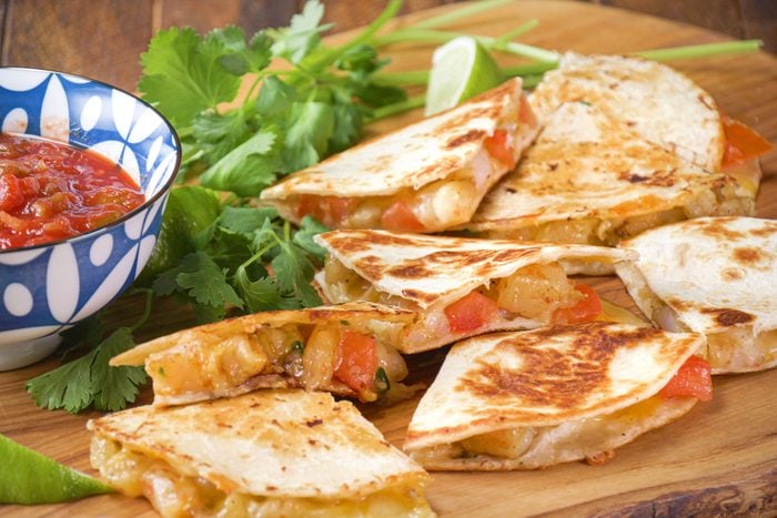 A plate of shrimp quesadillas served with a side bowl of salsa, perfect for a delicious and flavorful meal