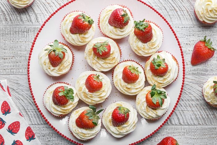 Strawberry Cheesecake Cupcakes arranged on a large plate on a wooden surface