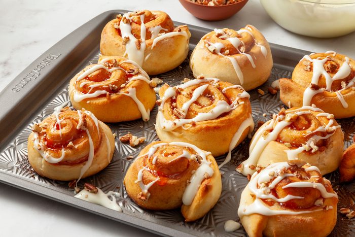 Strawberry Cinnamon Rolls glazed and topped with pecans on baking tray