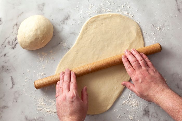Rolling the dough on flat surface with rolling pin
