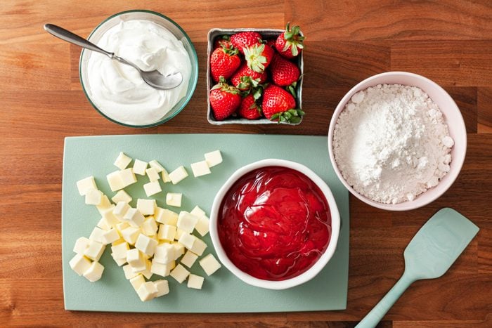 Strawberry pie filling White cake mix Butter and other ingredients on a wooden table