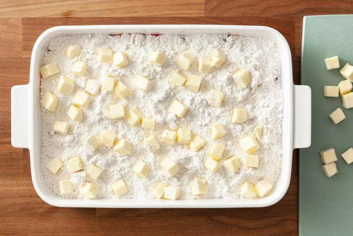 Butter cubes lined on cake mixture on a baking pan