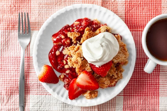 Strawberry Dump Cake in a plate with cream and coffee