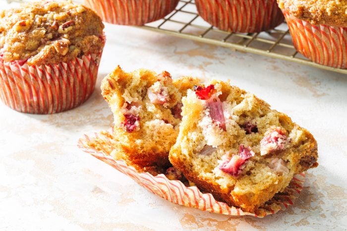 A strawberry rhubarb muffin with a bite taken out of it